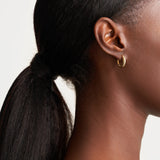 Model wearing 14k yellow gold tapered hoop earrings, styled for a minimalist everyday look.