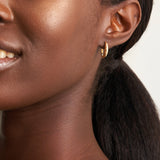 Model wearing 14k yellow gold tapered hoop earrings, styled for a minimalist everyday look