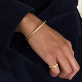 Lifestyle shot of the gold Tubogas ring worn with the cord bangle