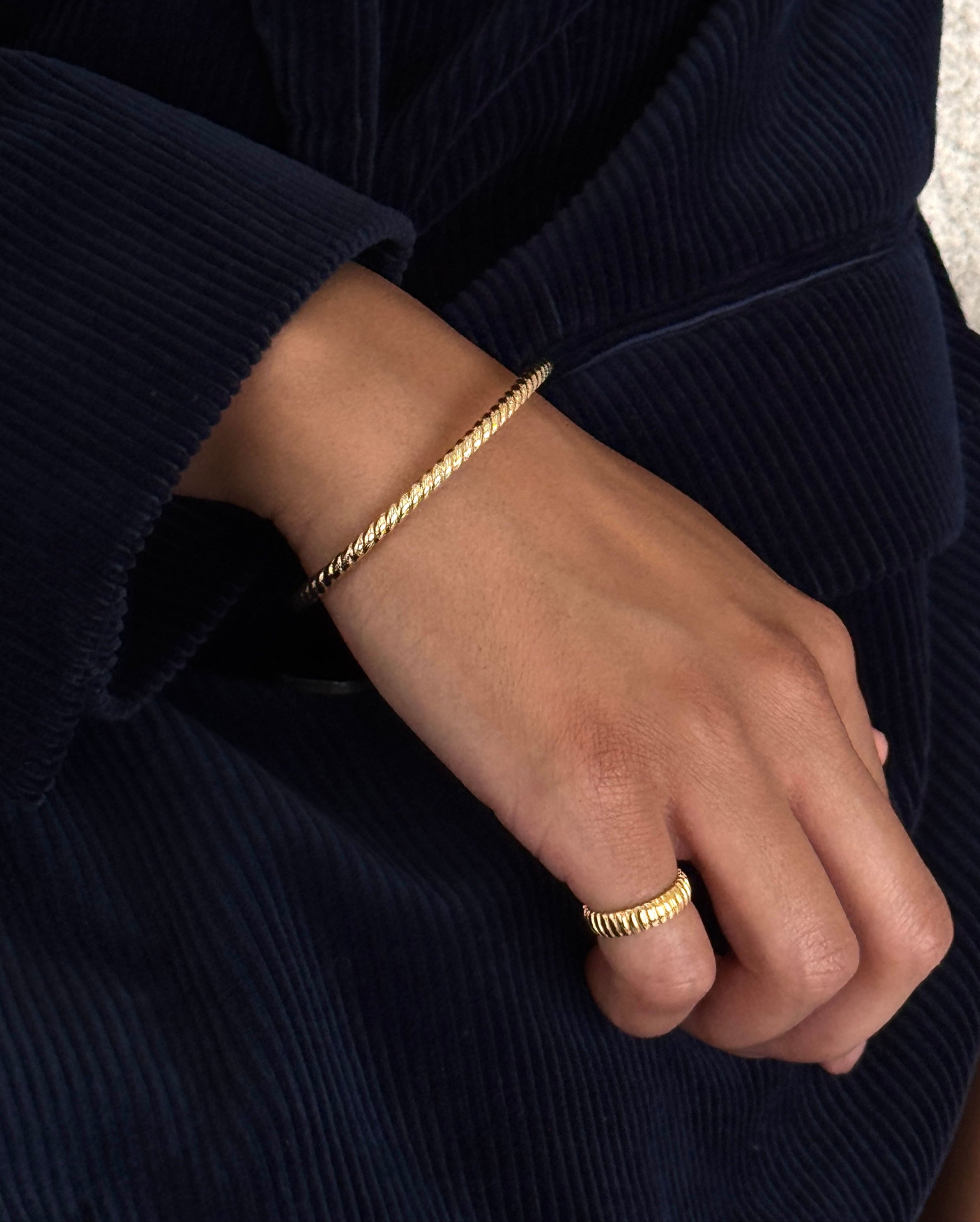 Lifestyle shot of the gold Tubogas ring worn with the cord bangle